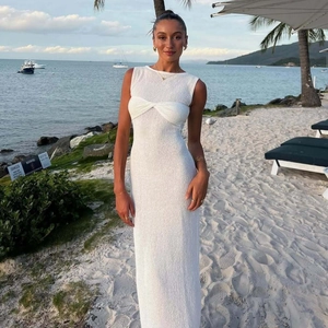 Detail view of white sleeveless maxi dress with twisted bust design on a sunny beach