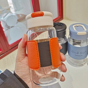 Close-up of glass tea infuser bottle with orange and black leather thermal sleeve