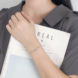 Adjustable silver heart bracelet with cubic zirconia on a minimalist magazine background