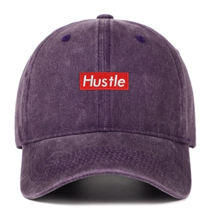 Close-up of a washed purple baseball cap featuring a red rectangle Hustle embroidery