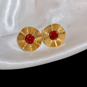 Makroaufnahme von Vintage-Goldohrringen mit rotem Stein auf weißem Plissee-Satin