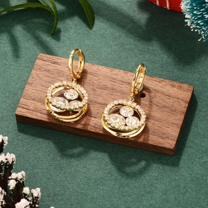 Macro shot of gold tassel earrings with clear zircons on a wooden display stand