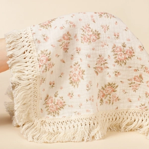 Detail of floral printed cotton baby blanket with soft tassels and breathable muslin texture