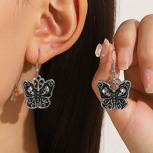Close-up of Gothic silver butterfly earrings with skull relief detail on model