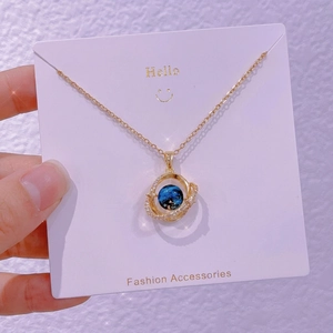 Dettaglio macro della collana a pianeta con pendente nebulosa blu e anelli di zirconi