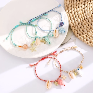 Close-up of four ocean-themed woven bracelets with starfish and shell charms