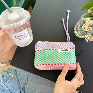 Detailed close-up of a colorful hand-woven striped makeup bag with top zipper and cord pull