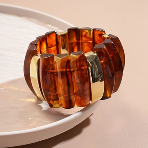 Close-up of amber acrylic and gold metal blocks on a stretch cuff bracelet