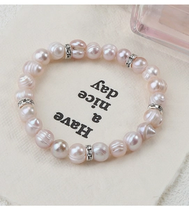 Dettaglio di perle rosa d'acqua dolce con distanziali in zircone su un biglietto regalo