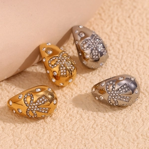 Macro detail of gold and gunmetal rings with bow-shaped white rhinestone inlay