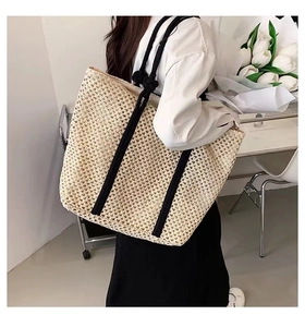 Detailed texture of beige hollow woven straw tote bag with black rope strap for women