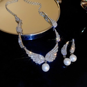 Macro shot of silver wing jewelry set with sparkling zircons and round white pearls