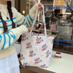 Detail of off-white corduroy tote bag with Keep Smiling print and logo patch