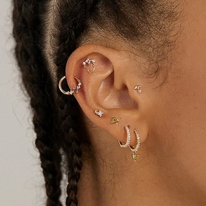 Macro view of gold S925 silver cartilage hoops and studs with zircon on model ear