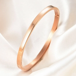 Close-up of a minimalist rose gold stainless steel bangle on white silk background
