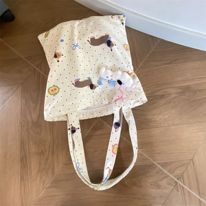 Detail view of cream canvas tote bag with dachshund print and fluffy white dog keychain