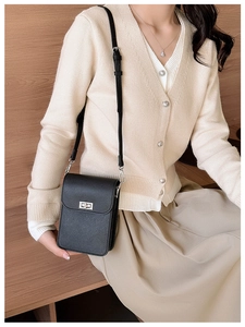 Mini black crossbody phone bag with crosshatch leather texture and silver buckle on model