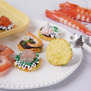 Modelli realistici di tortini di gamberetti artificiali su un piatto decorativo