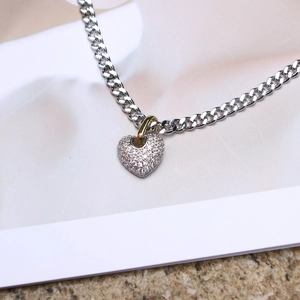 Close-up of heart pendant necklace with zircon paving and gold accent on cuban chain