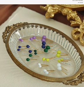 Macro shot of colorful double ball stud earrings on a luxury embossed vintage glass tray