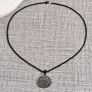 Close-up of matte black basketball pendant necklace with laser-engraved details and bead chain