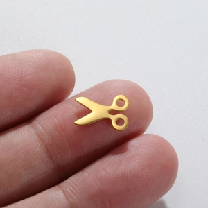 Polished 18K gold plated stainless steel scissor pendant shown on a fingertip