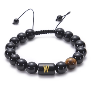 Detail of adjustable woven bracelet with black obsidian beads and golden letter W charm