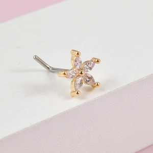 Macro shot of gold floral nose stud with sparkling crystals on a bicolor background
