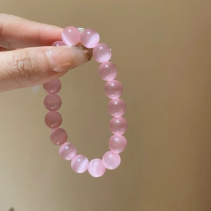 Macro detail of pink cat eye stone beads showing lustrous light reflection and smooth surface