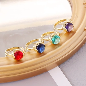 Detail of four colorful faceted zircon rings in gold settings with red and blue stones