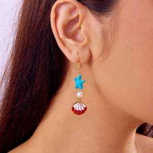 Detail of starfish and shell earrings featuring pearls on a model for a coastal look