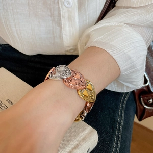 Detail of vintage textured heart bracelets in gold, silver, and rose gold on wrist
