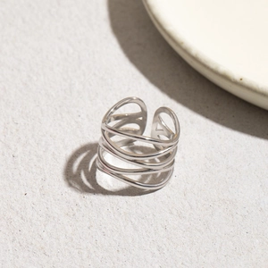 Detail of minimalist multilayered silver stainless steel wrap ring on stone background