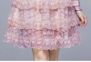 Détails de la robe en dentelle rose montrant la broderie florale et l'ourlet à volants