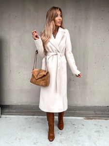 Detail of a creamy white long wool coat with waist tie belt and large lapels
