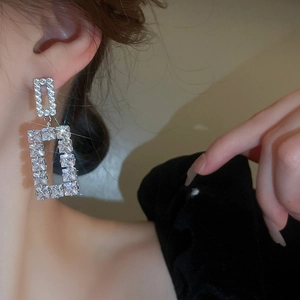 Close-up of double rectangular zircon drop earrings worn by a model in silver finish