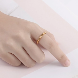 Close-up of golden bamboo-style minimalist ring worn on finger with soft lighting