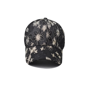 Close-up of black baseball cap with intricate silver flower embroidery and curved brim