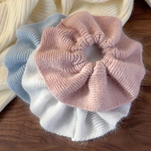 Knitted pleated hair scrunchies in pink, white and blue colors on wooden surface