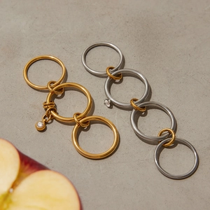 Detail of layered titanium steel rings with zircon charms on a textured stone surface
