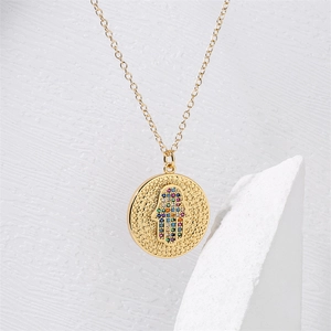 Détail du collier pendentif main de Hamsa dorée avec micro-incrustations de zircons colorés