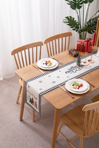 Close-up of Merry Christmas table runner with buffalo plaid pattern on a wooden dining table