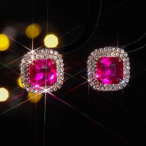 Detailed view of ruby red square stud earrings with halo diamonds and star flare