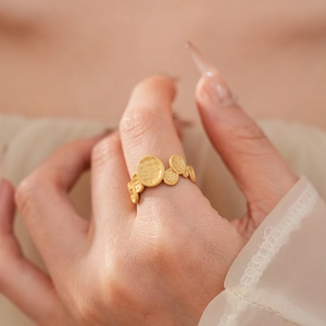 Macro shot of gold oval ring with hammered texture and wrinkled design on model finger