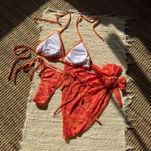 Vue détaillée d'un bikini imprimé paisley orange avec haut licou et paréo assorti