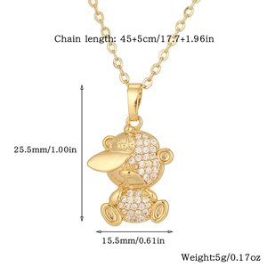 Detail view of a gold bear pendant with rhinestones and engraved cool hat on a white base