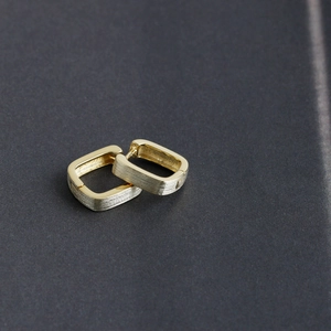 Detailed macro view of gold rectangular hoop earrings with brushed and polished dual finish