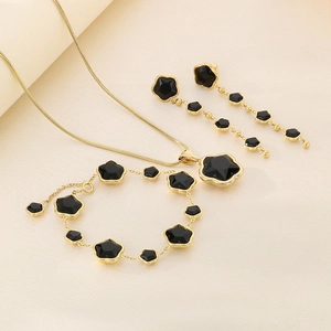 Detailed set of gold necklace, bracelet and earrings featuring black star shaped stones