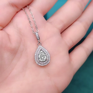 Macro shot of silver pear-cut olive green zircon necklace with double diamond halo detail
