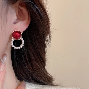 Close-up of vintage earrings with red pearl and white pearl circle on golden metal